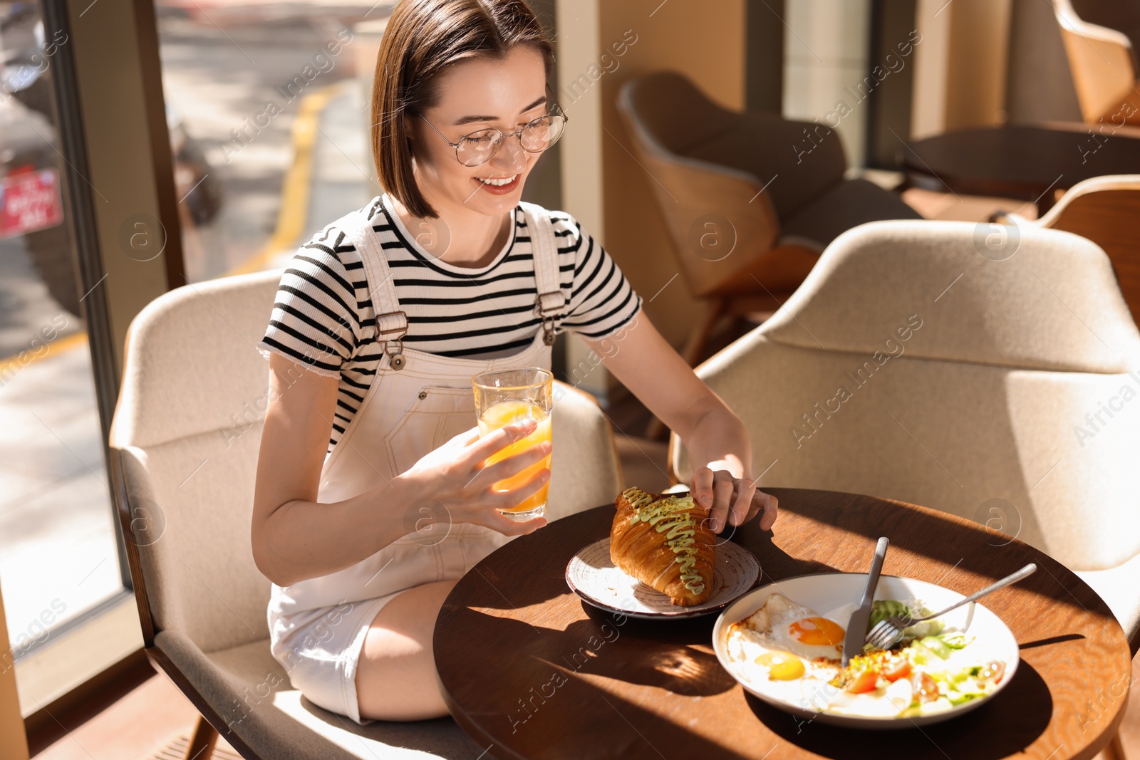 Photo of Happy woman having tasty breakfast in cafe