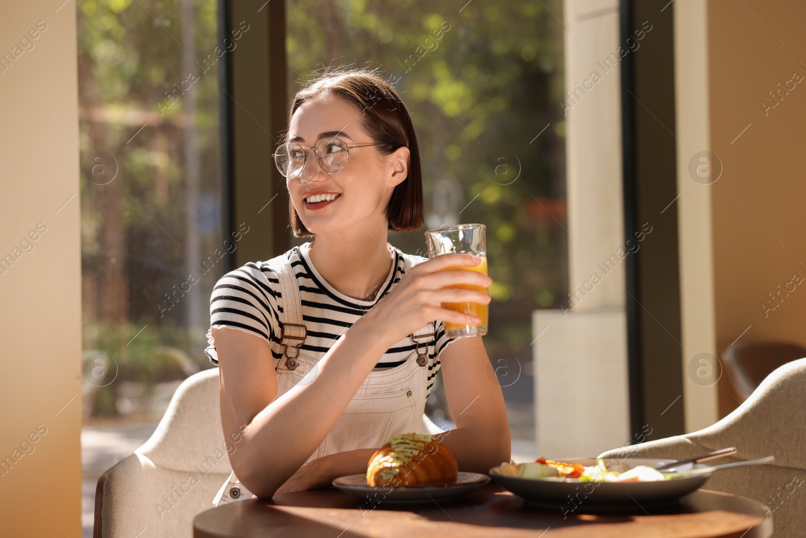 Photo of Happy woman having tasty breakfast in cafe, space for text