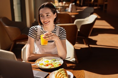 Photo of Happy woman having tasty breakfast in cafe, space for text