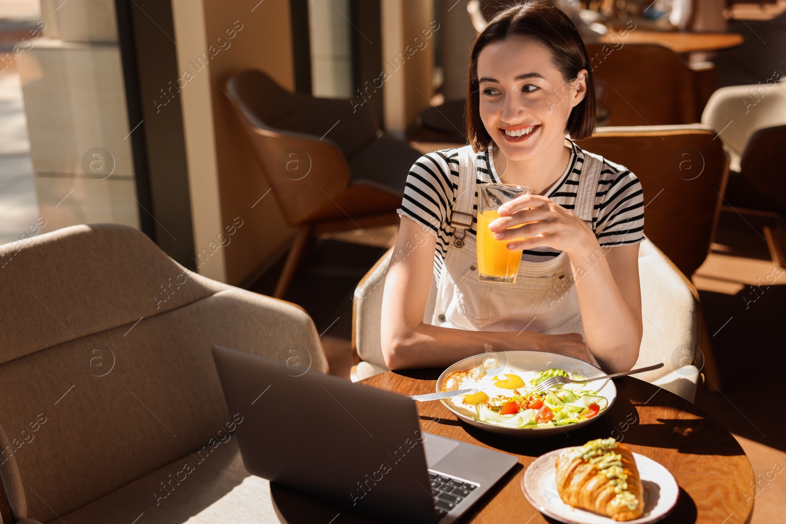 Photo of Happy woman having tasty breakfast in cafe