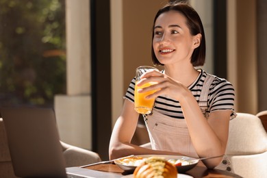 Happy woman having tasty breakfast in cafe