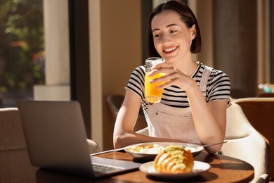 Happy woman having tasty breakfast in cafe