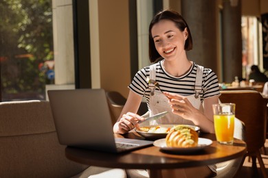 Happy woman having tasty breakfast in cafe