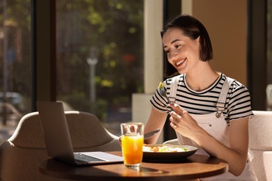 Happy woman having tasty breakfast in cafe