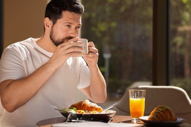 Photo of Handsome man having tasty breakfast in cafe