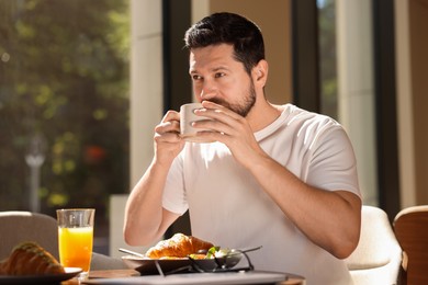 Photo of Handsome man having tasty breakfast in cafe