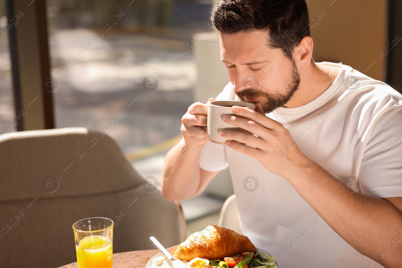 Photo of Handsome man having tasty breakfast in cafe