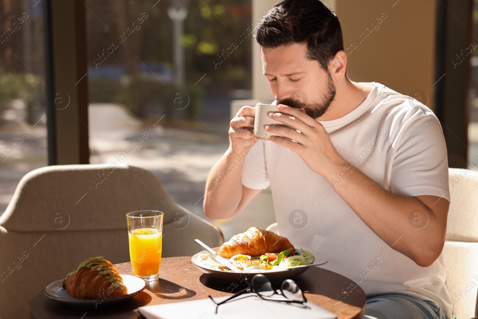 Photo of Handsome man having tasty breakfast in cafe