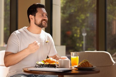 Happy man having tasty breakfast in cafe