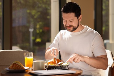 Happy man having tasty breakfast in cafe