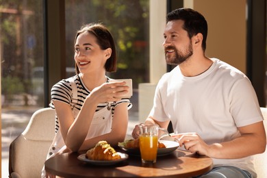 Photo of Happy couple having tasty breakfast in cafe