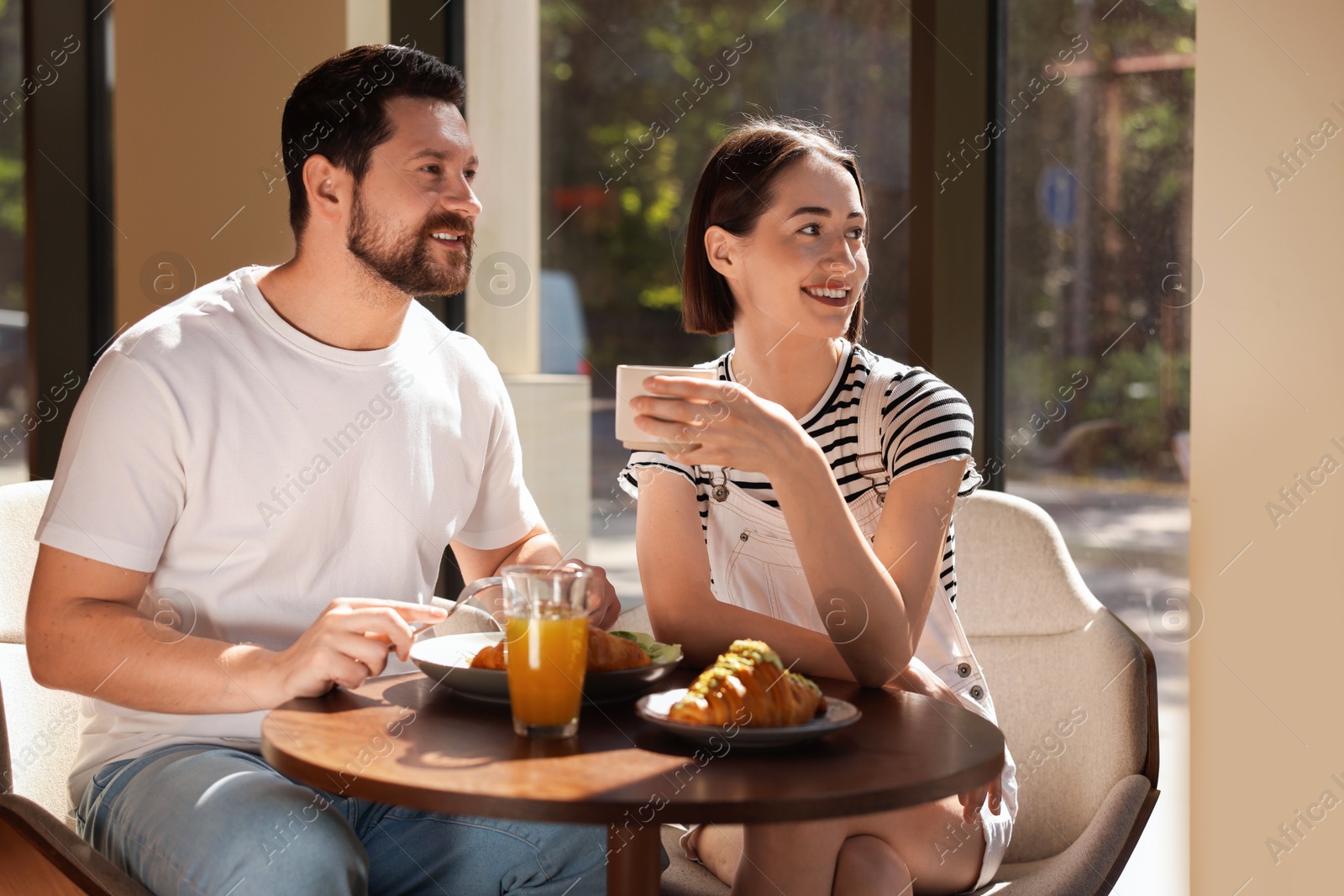 Photo of Happy couple having tasty breakfast in cafe