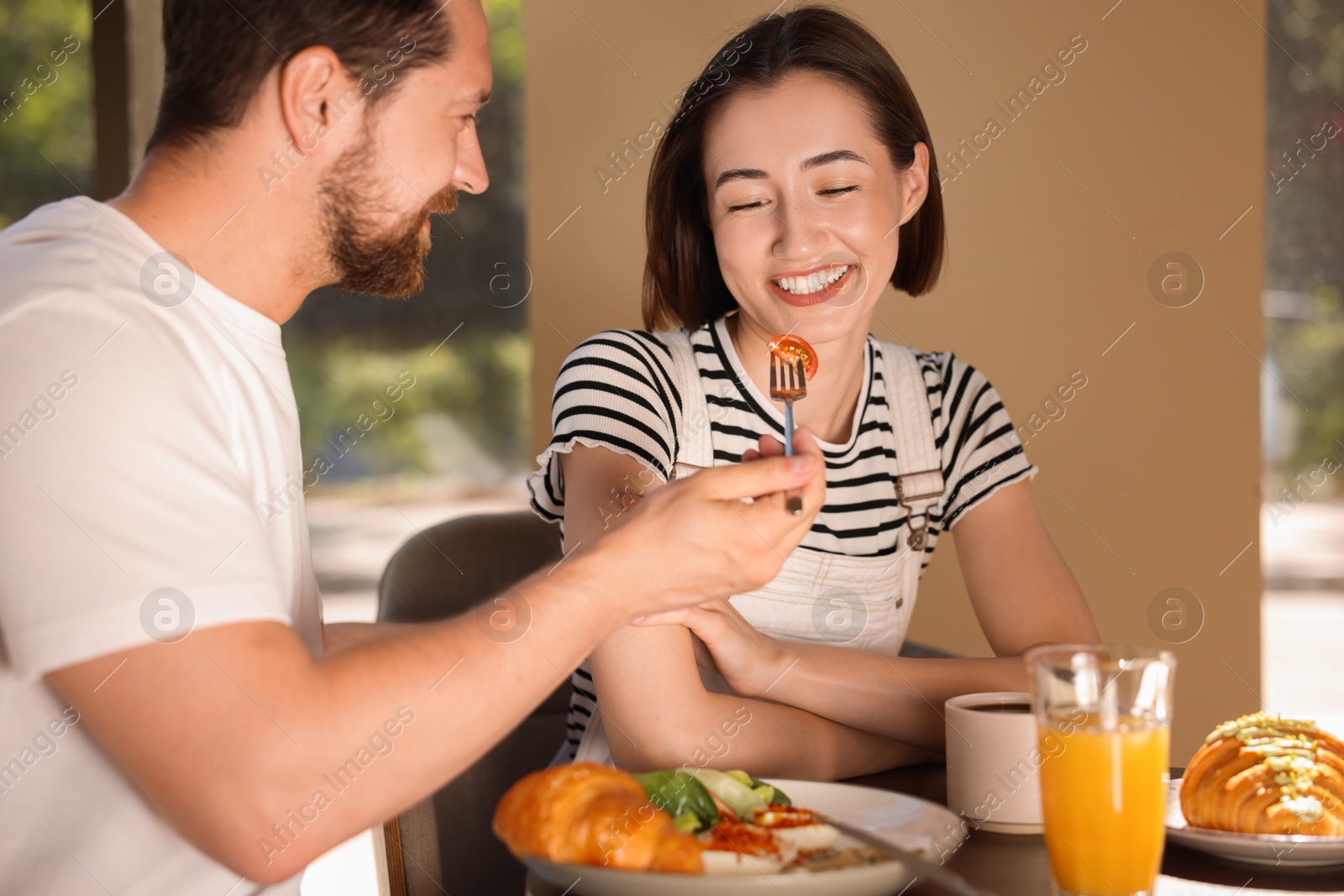 Photo of Happy couple having tasty breakfast in cafe