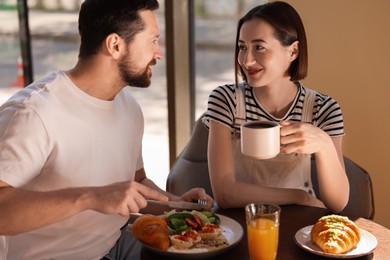 Photo of Happy couple having tasty breakfast in cafe