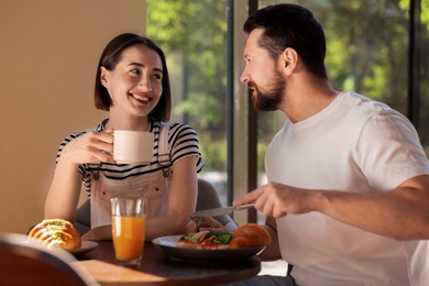 Happy couple having tasty breakfast in cafe