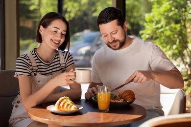 Photo of Happy couple having tasty breakfast in cafe