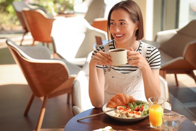 Photo of Happy woman having tasty breakfast in cafe