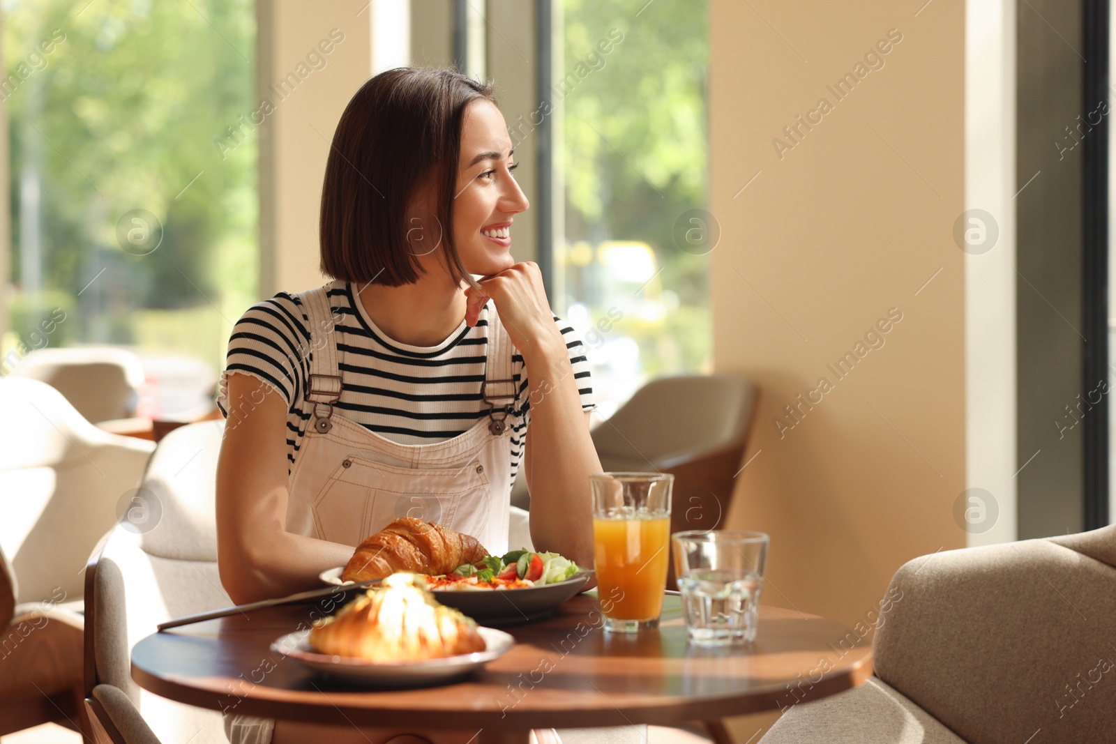 Photo of Happy woman having tasty breakfast in cafe, space for text