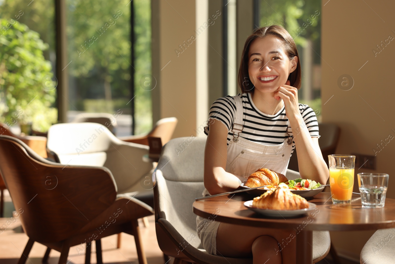 Photo of Happy woman having tasty breakfast in cafe