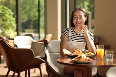 Photo of Happy woman having tasty breakfast in cafe