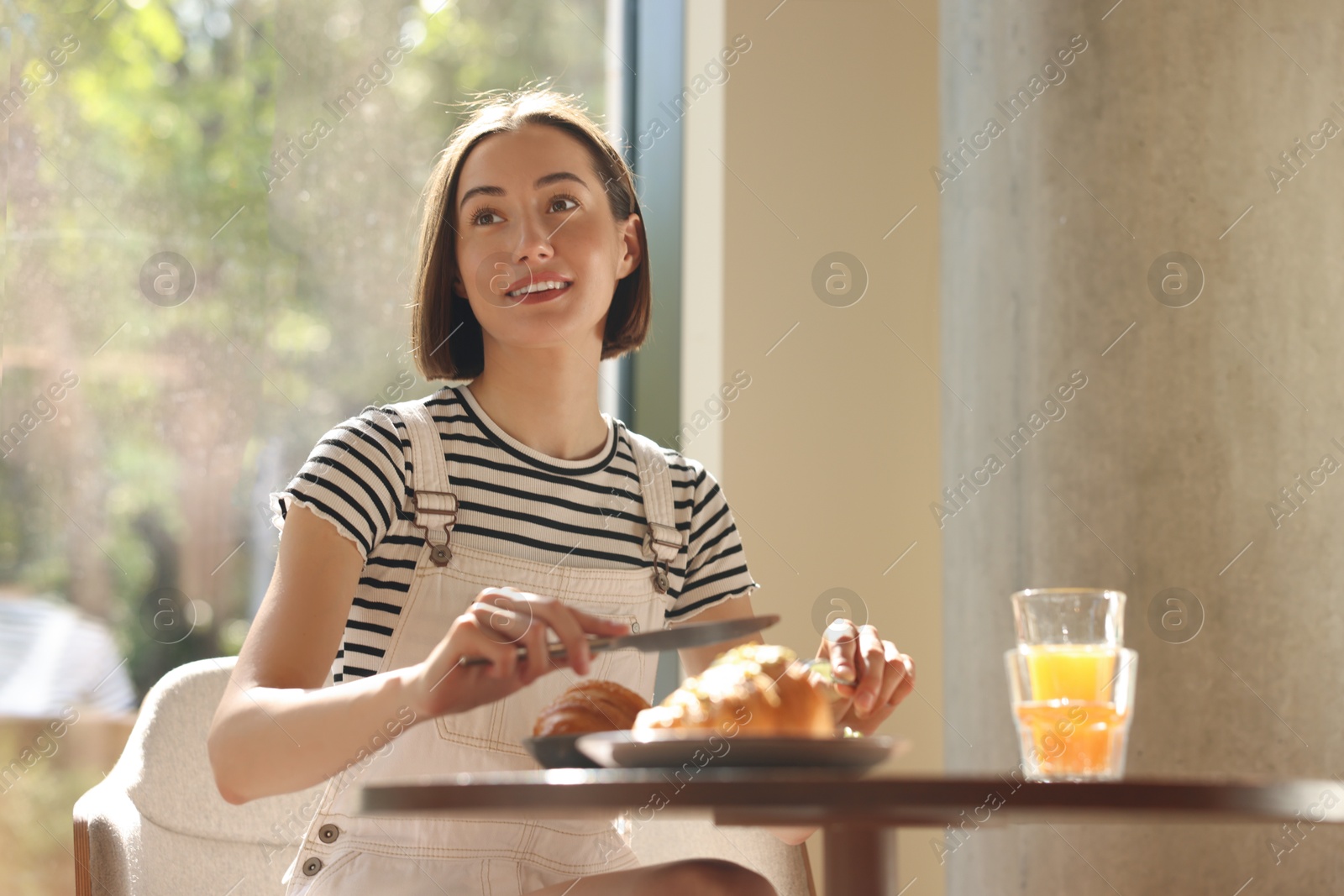 Photo of Happy woman having tasty breakfast in cafe