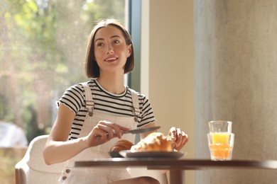 Happy woman having tasty breakfast in cafe