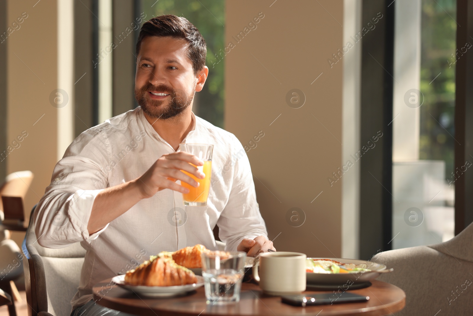 Photo of Happy man having tasty breakfast in cafe, space for text