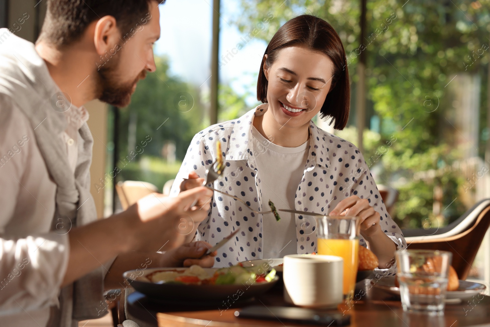 Photo of Happy couple having tasty breakfast in cafe