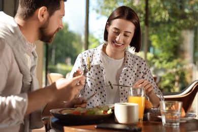 Happy couple having tasty breakfast in cafe