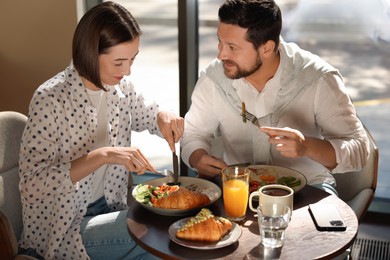 Happy couple having tasty breakfast in cafe