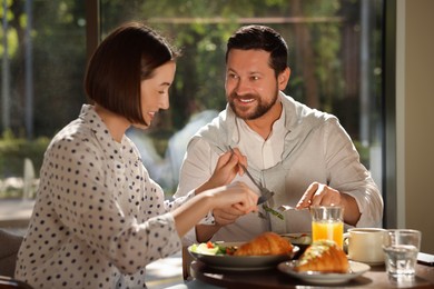 Happy couple having tasty breakfast in cafe