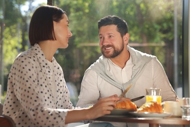 Photo of Happy couple having tasty breakfast in cafe