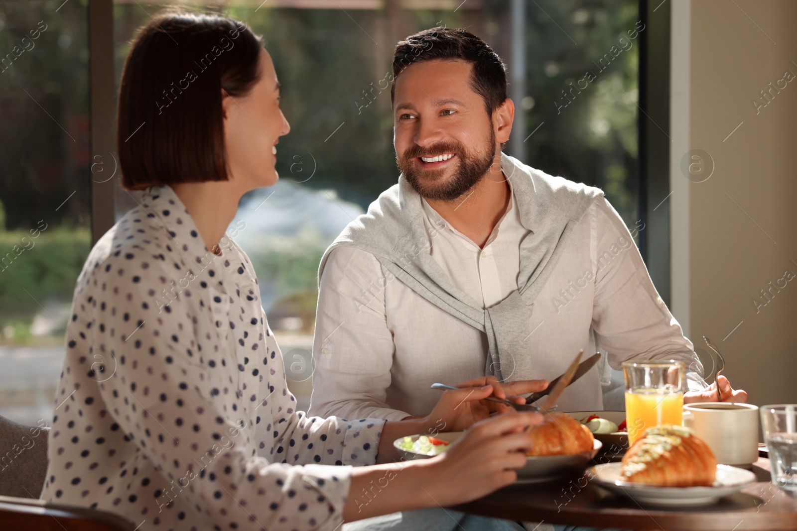 Photo of Happy couple having tasty breakfast in cafe