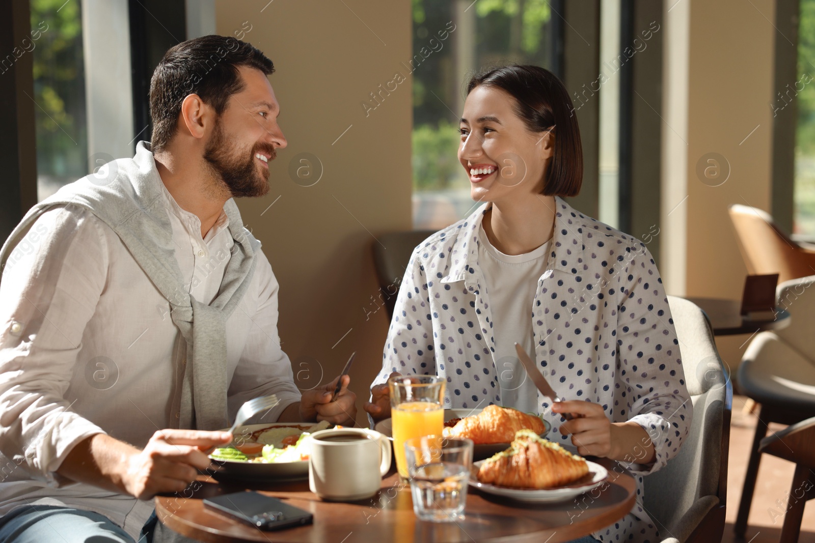 Photo of Happy couple having tasty breakfast in cafe