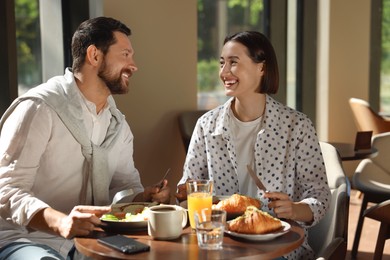 Happy couple having tasty breakfast in cafe