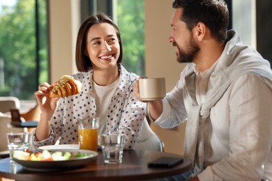 Photo of Happy couple having tasty breakfast in cafe