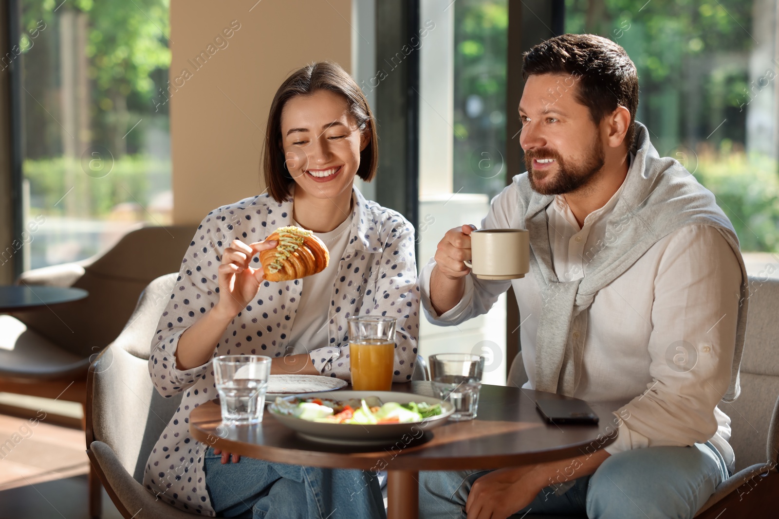 Photo of Happy couple having tasty breakfast in cafe