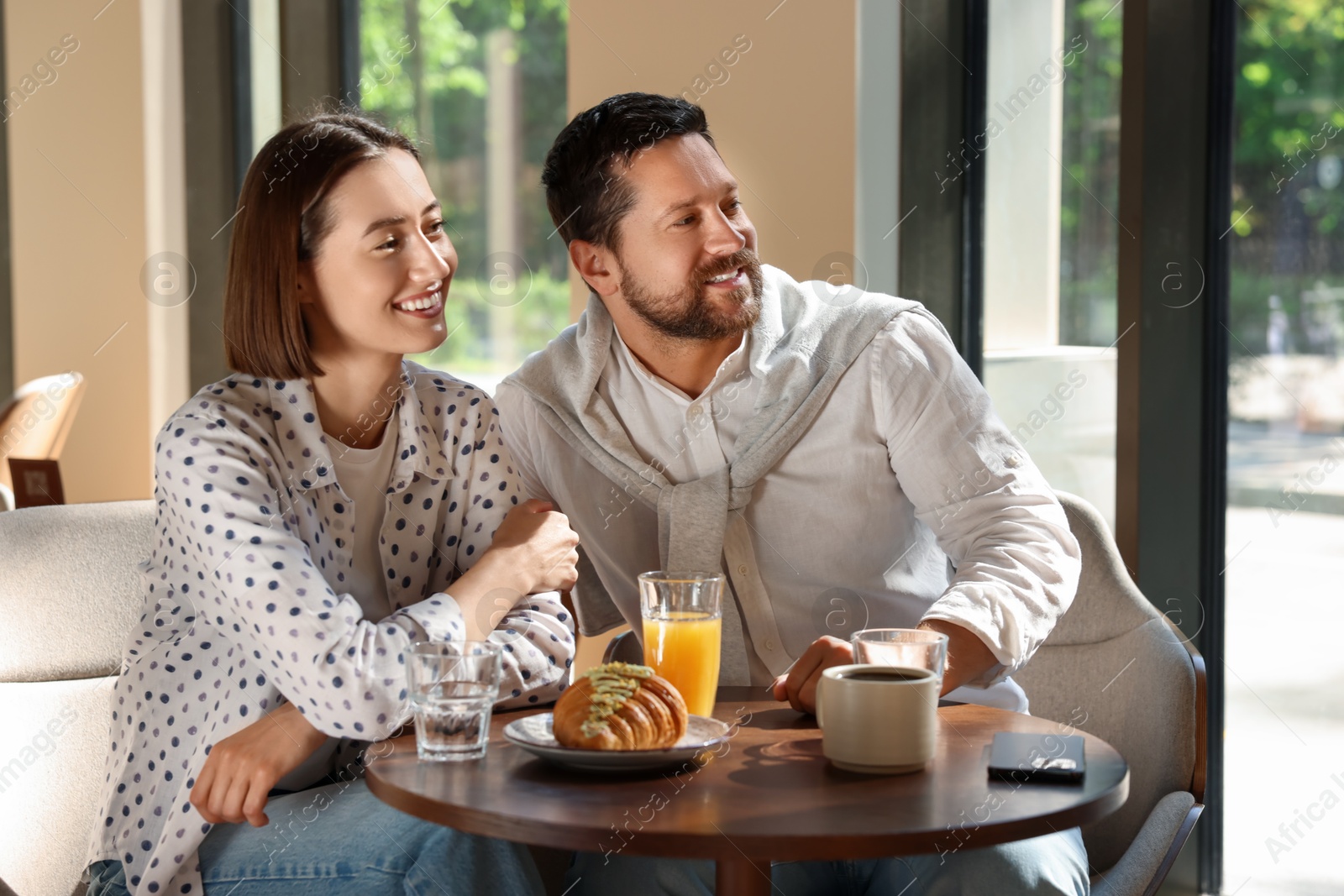 Photo of Happy couple having tasty breakfast in cafe