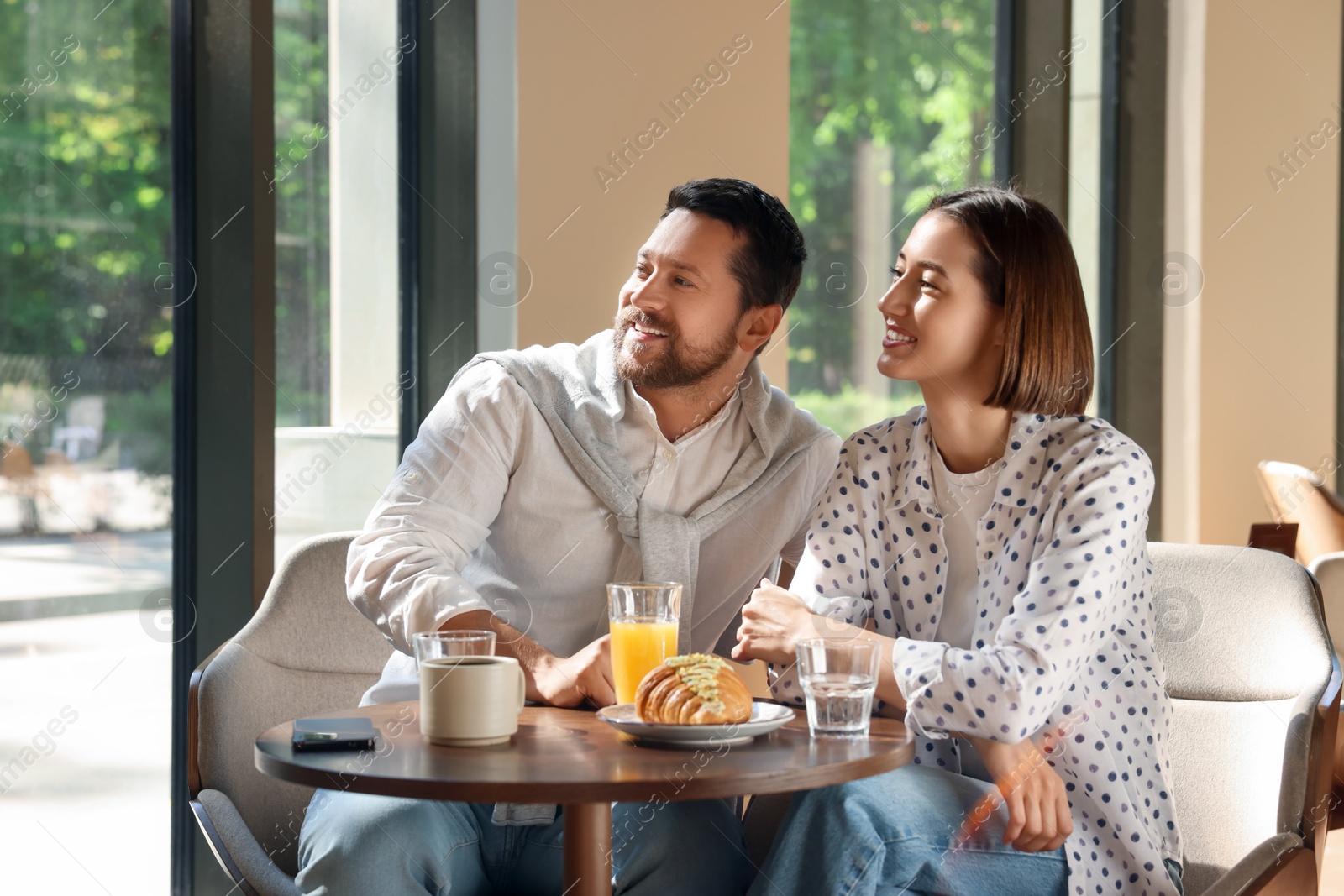 Photo of Happy couple having tasty breakfast in cafe