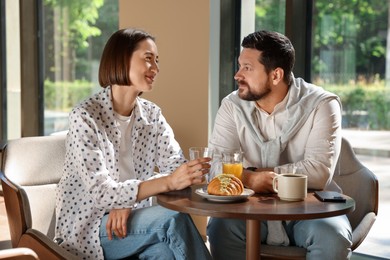 Happy couple having tasty breakfast in cafe