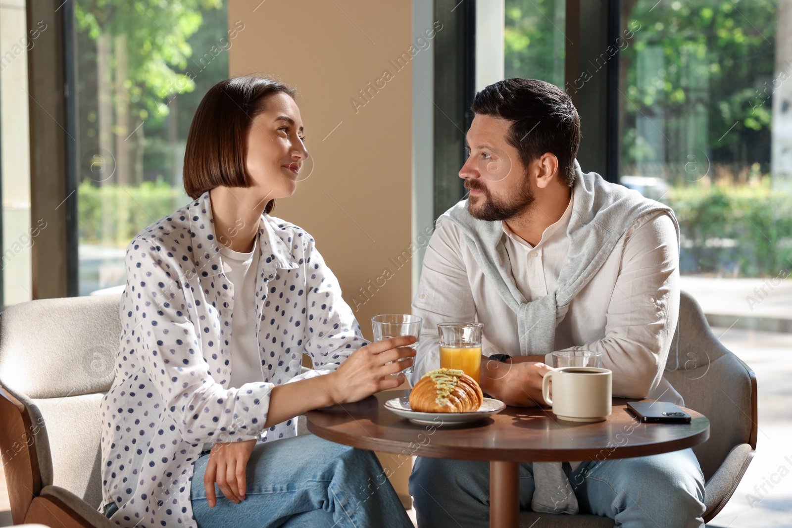 Photo of Happy couple having tasty breakfast in cafe