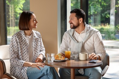 Photo of Happy couple having tasty breakfast in cafe