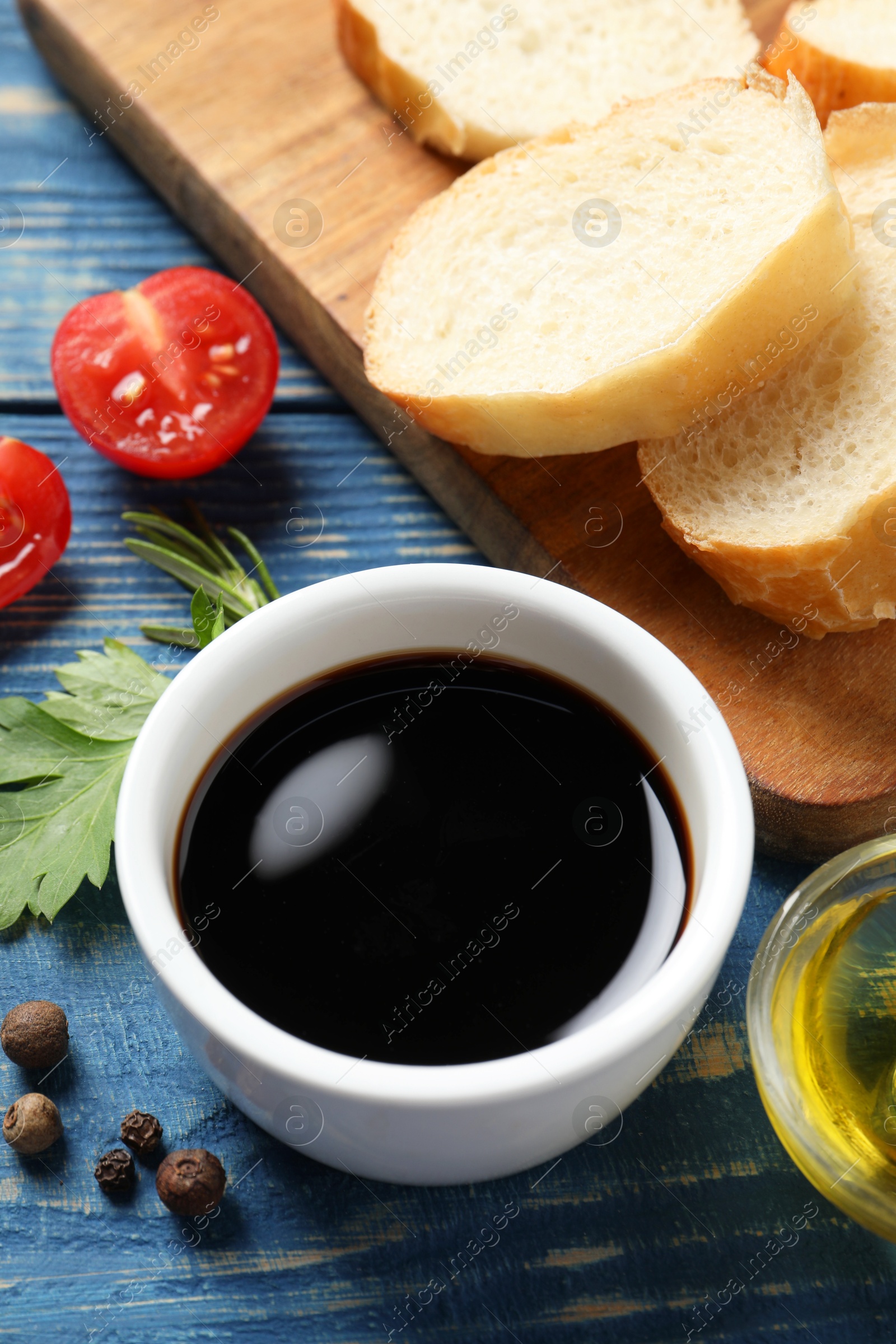 Photo of Balsamic vinegar, bread and other products on blue wooden table