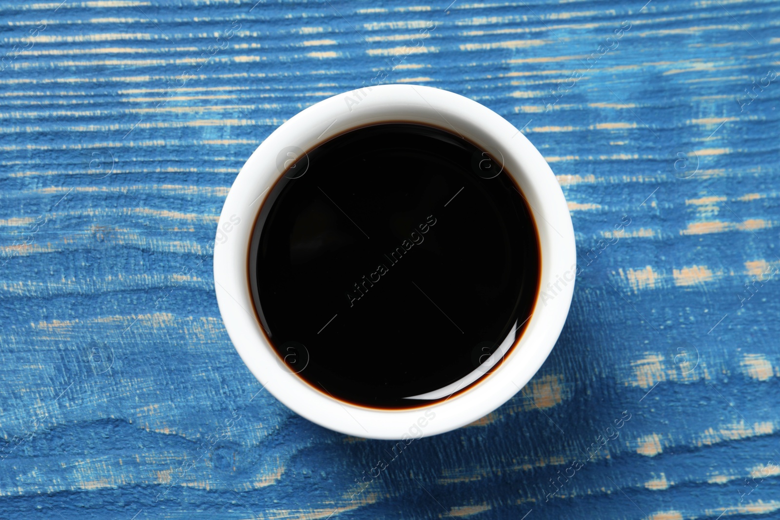 Photo of Balsamic vinegar on blue wooden table, top view