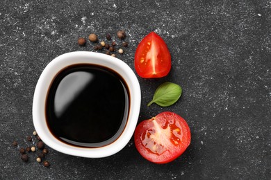 Photo of Balsamic vinegar, tomato and other products on black textured table, flat lay. Space for text