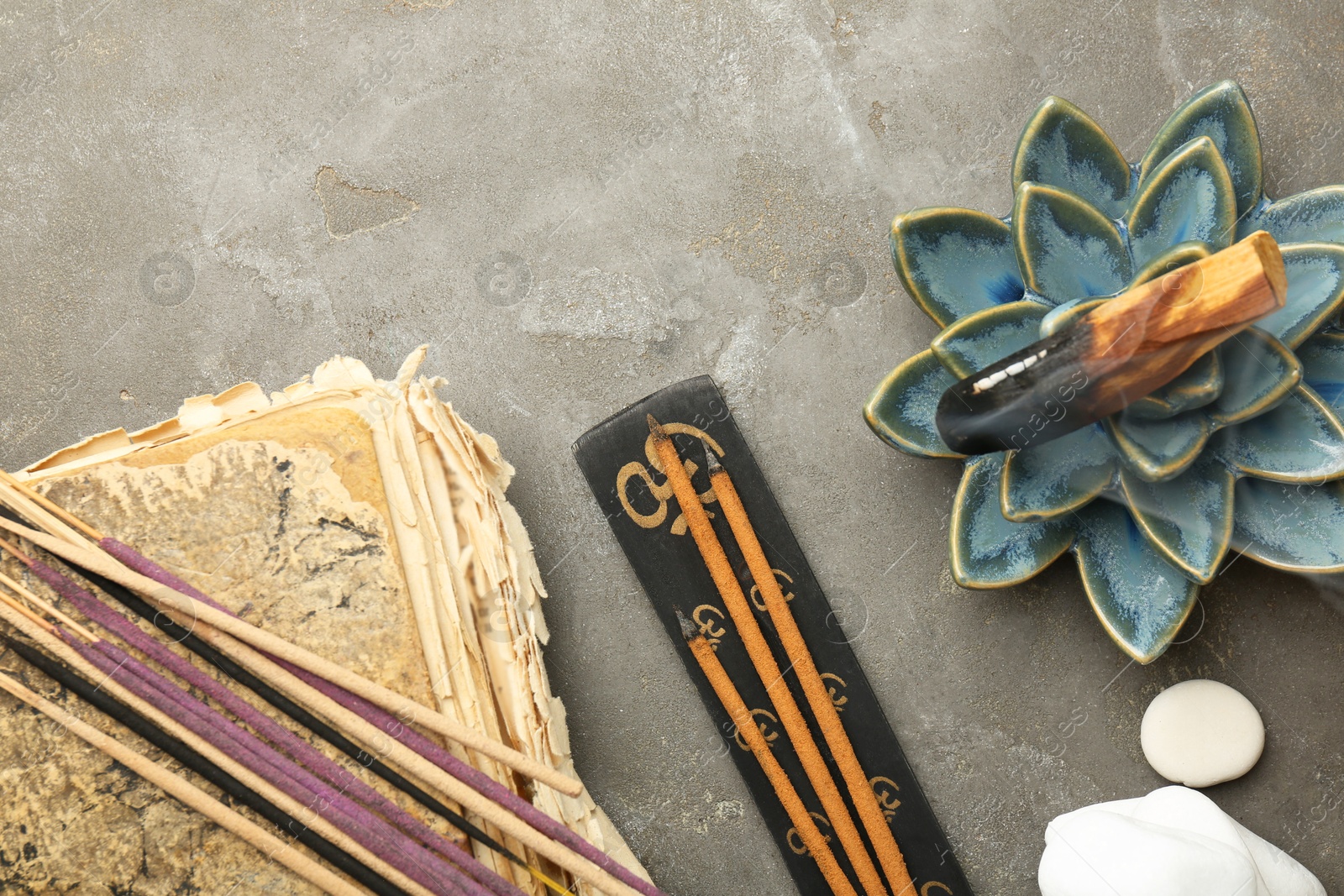 Photo of Flat lay composition with incense sticks on gray textured table. Om ligature