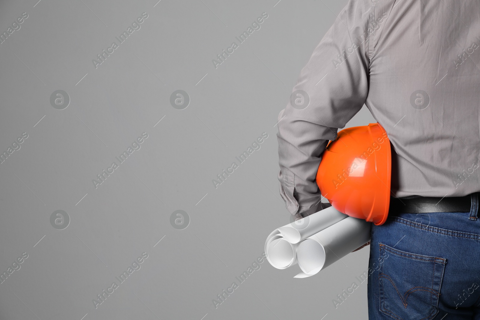 Photo of Engineer with hard hat and drafts on grey background, closeup. Space for text