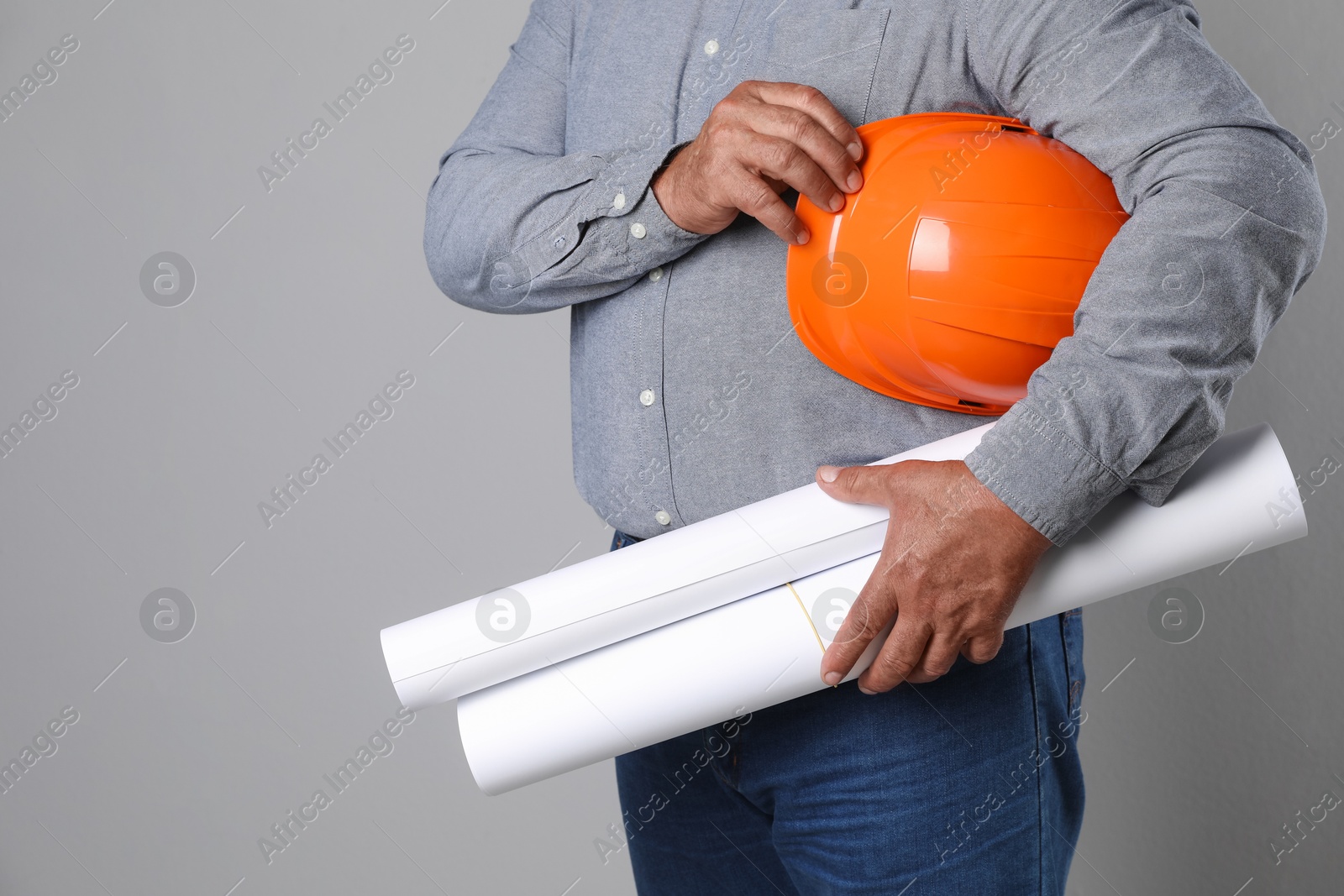 Photo of Engineer with hard hat and drafts on grey background, closeup. Space for text