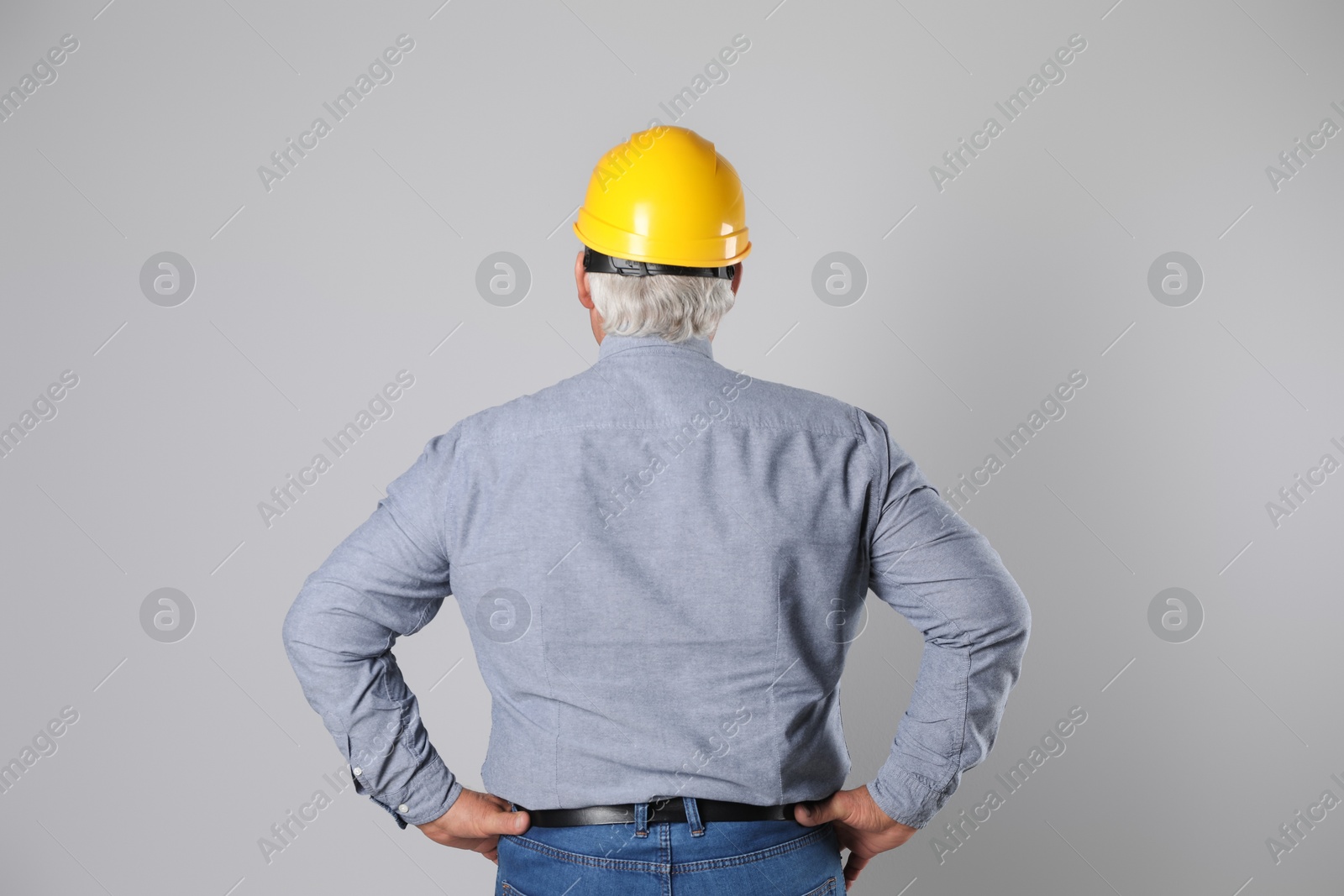 Photo of Engineer in hard hat on grey background, back view