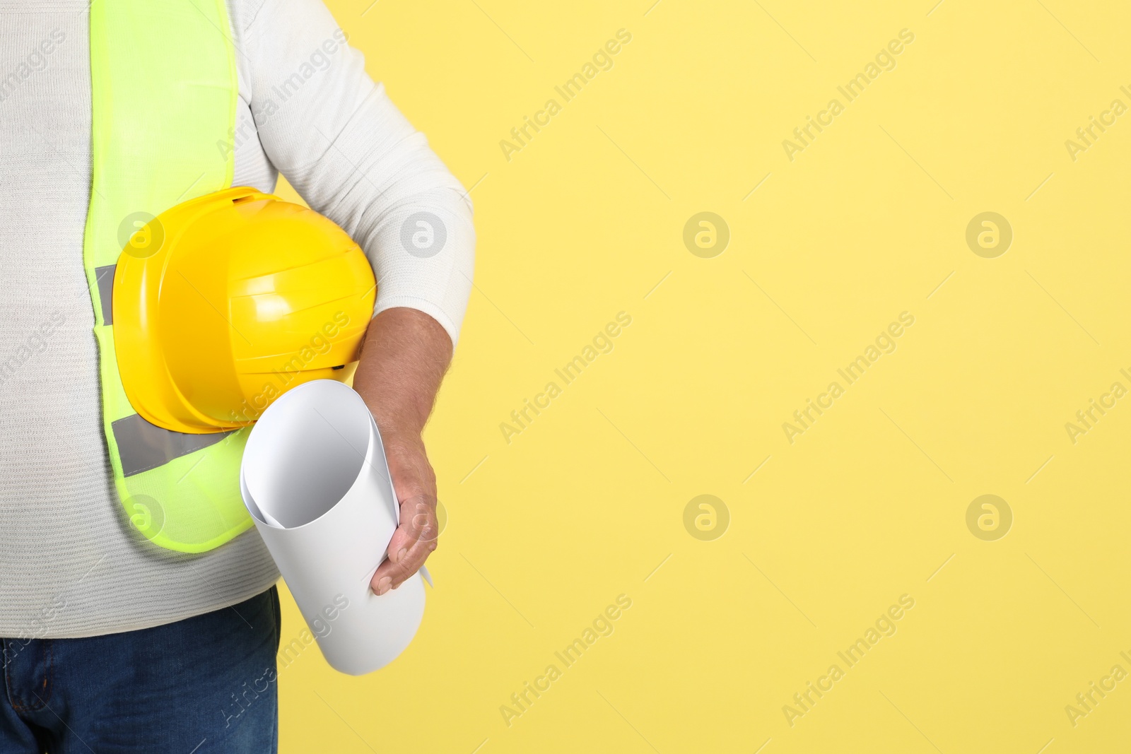 Photo of Engineer with hard hat and draft on yellow background, closeup. Space for text